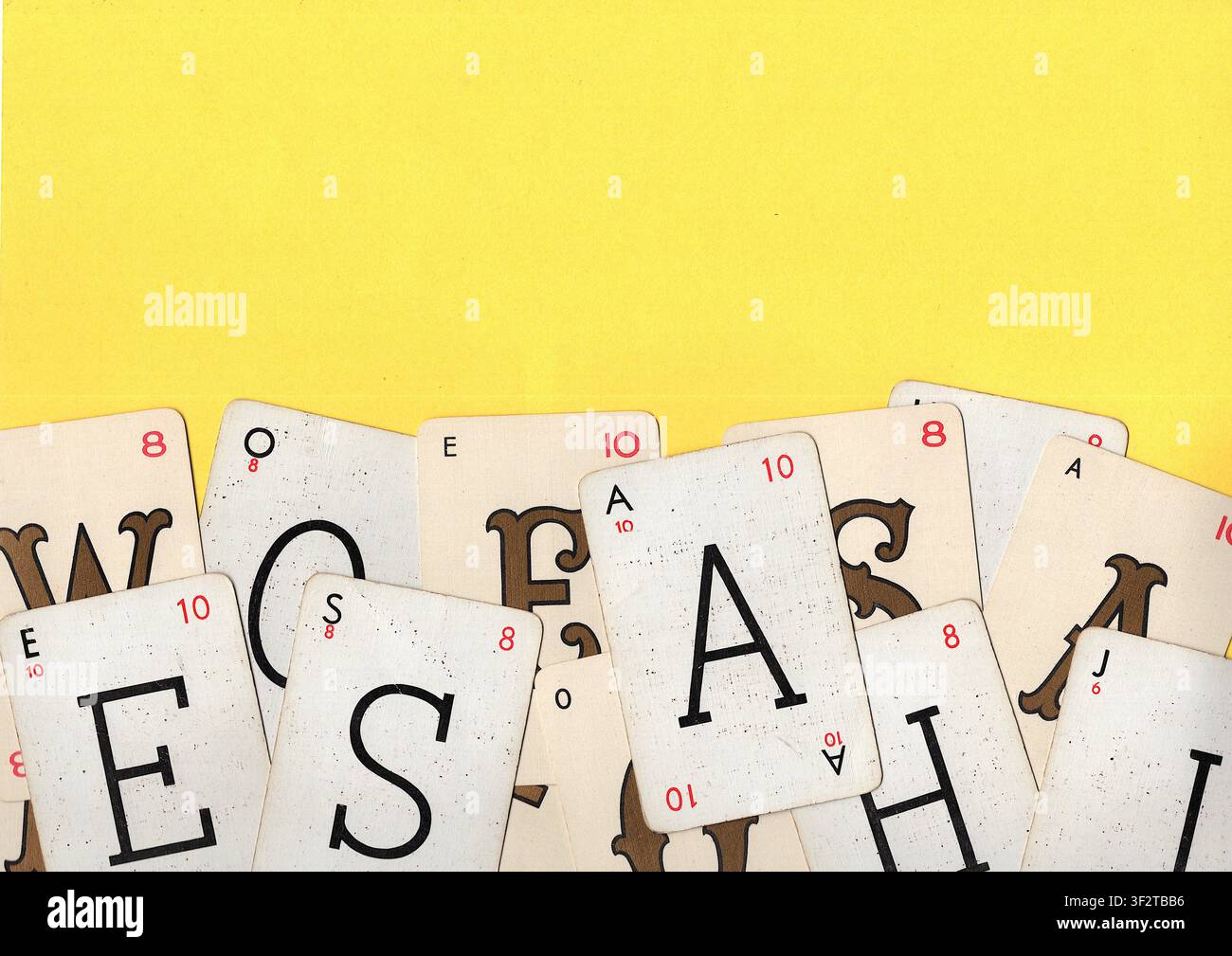 Un montaggio di carte da gioco alfabetiche vintage su uno sfondo giallo brillante con spazio per testo o copia. Foto Stock