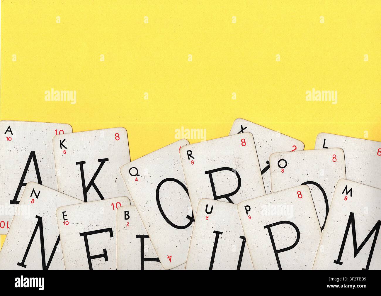 Un montaggio di carte da gioco alfabetiche vintage su uno sfondo giallo brillante con spazio per testo o copia. Foto Stock