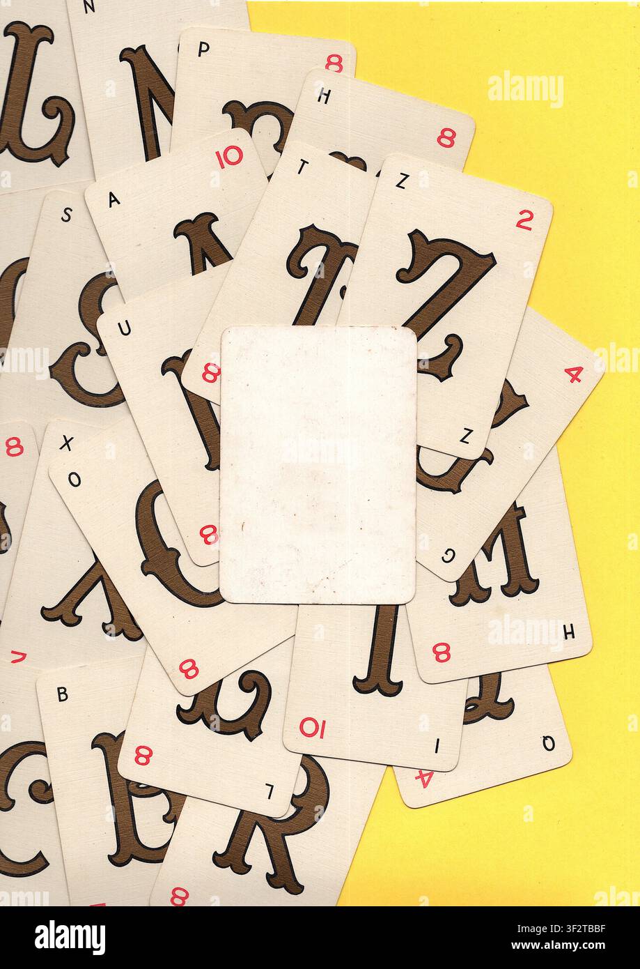 Un montaggio di carte da gioco alfabetiche vintage su uno sfondo giallo brillante con spazio per testo o copia. Foto Stock
