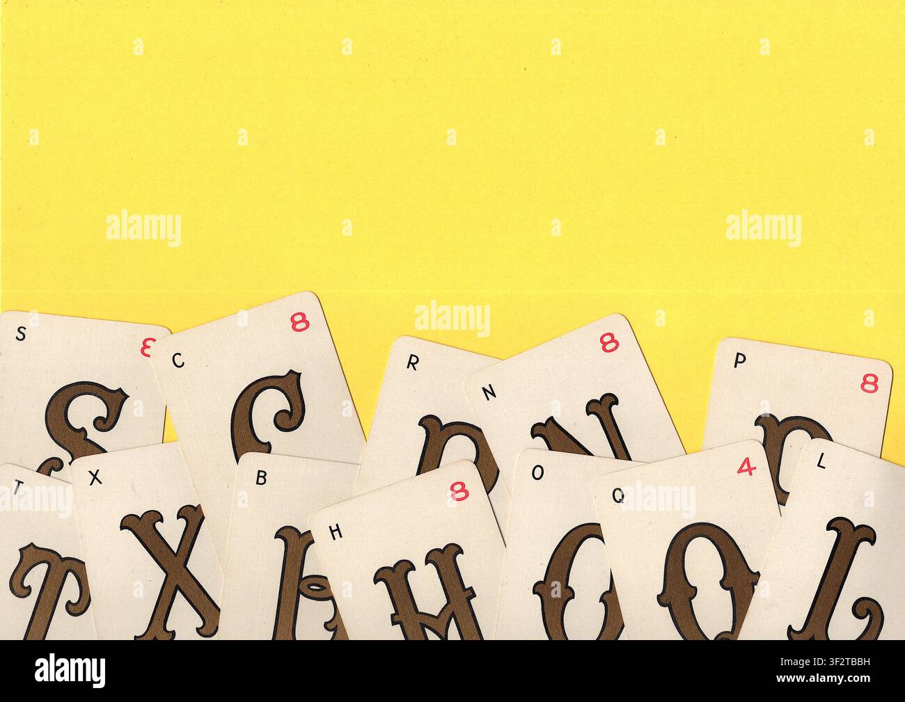 Un montaggio di carte da gioco alfabetiche vintage su uno sfondo giallo brillante con spazio per testo o copia. Foto Stock