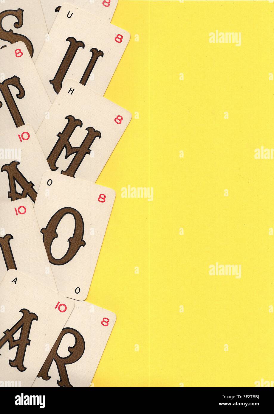 Un montaggio di carte da gioco alfabetiche vintage su uno sfondo giallo brillante con spazio per testo o copia. Foto Stock