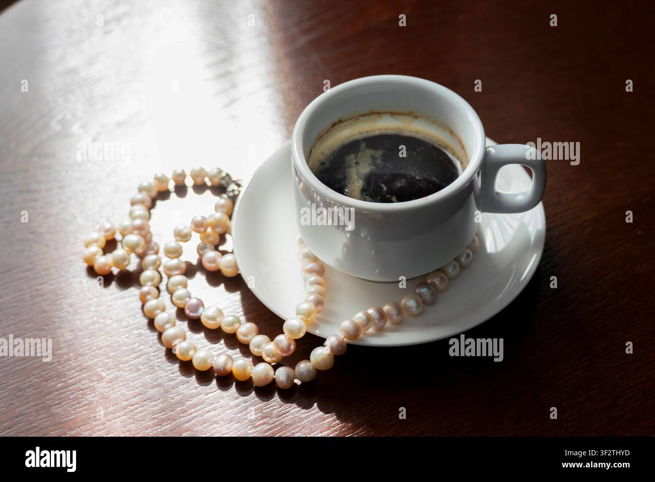 un'immagine filosofica astratta di caffè incompiuto con una collana di perle sul tavolo significato della vita Foto Stock