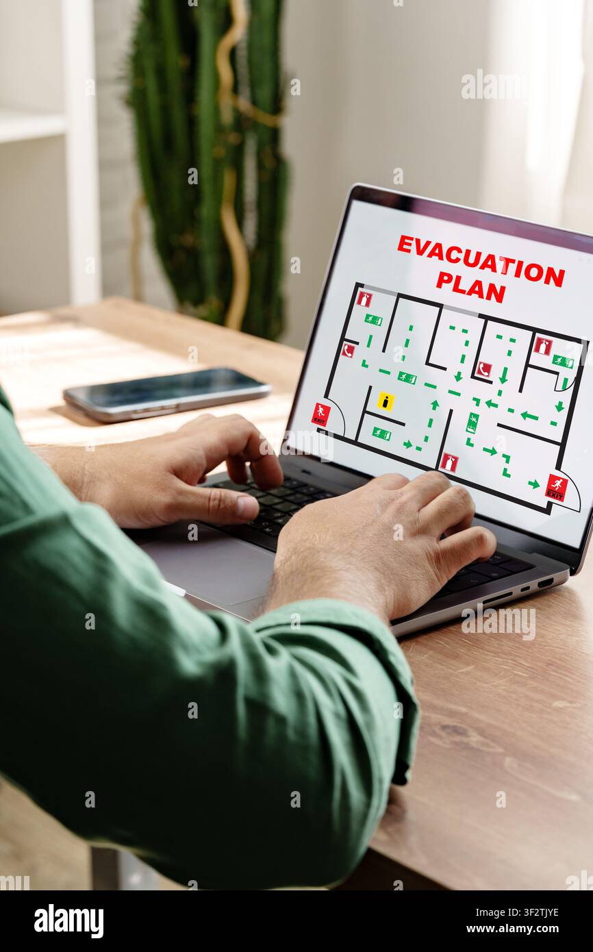 L'utente studia il piano di evacuazione per le risposte di emergenza sul posto di lavoro Foto Stock
