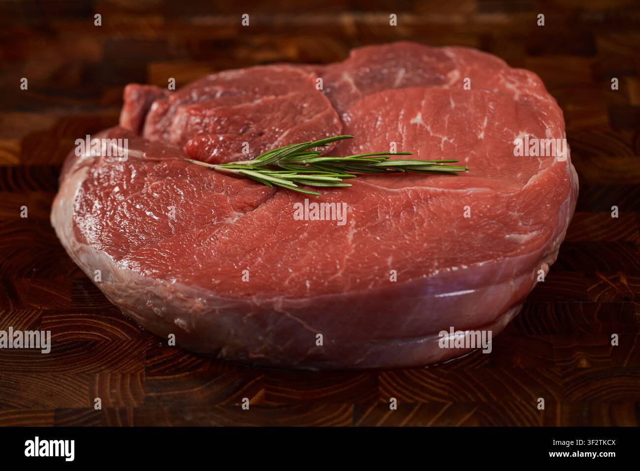 Bistecca di manzo crudo con rosmarino su tagliere Foto Stock