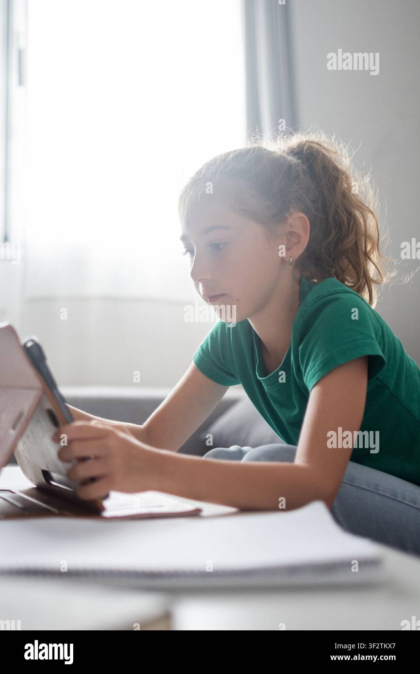 Scolaretta concentrata che utilizza un tablet per l'apprendimento online a casa Foto Stock
