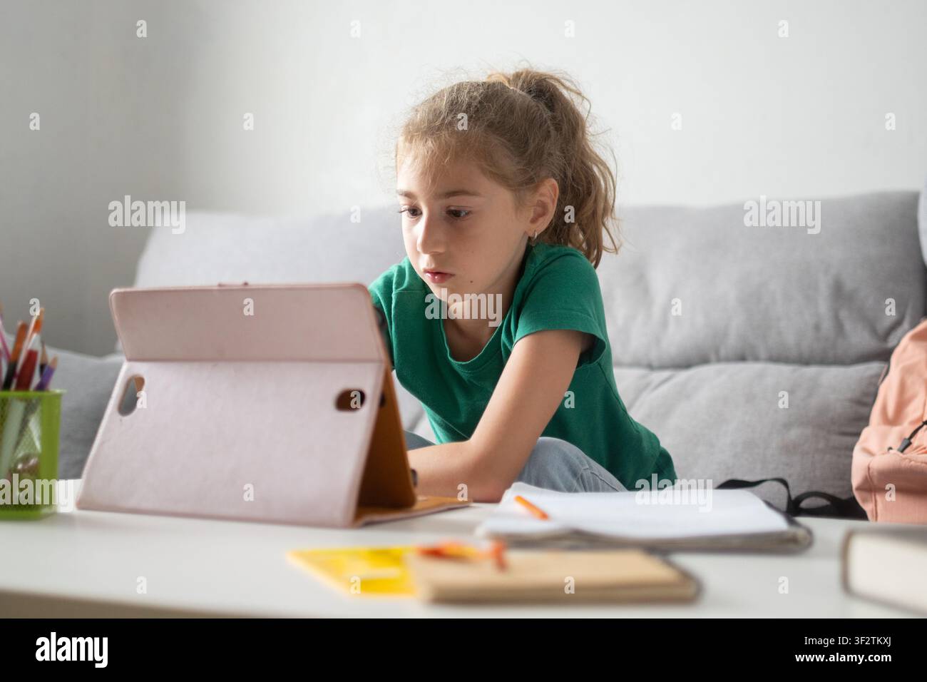 Scolaretta concentrata che utilizza un tablet per l'apprendimento online a casa Foto Stock