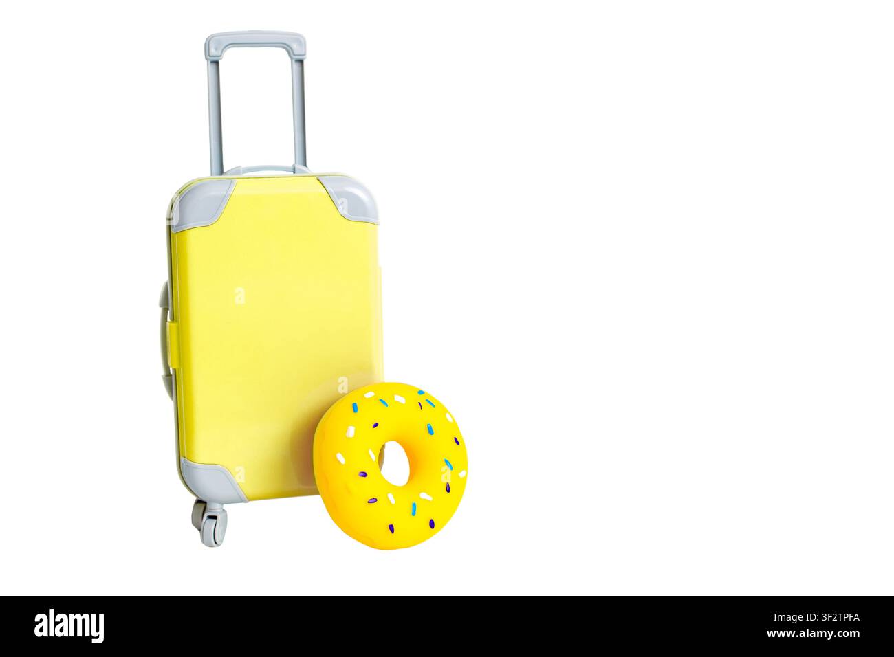 Una valigia gialla sulle ruote e un cerchio giallo per nuotare si stagliano su un ampio sfondo bianco. Foto Stock
