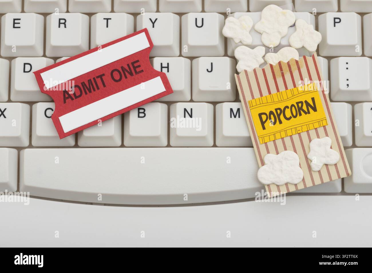 Popcorn e biglietto su una tastiera bianca del computer per il binge-watching online Foto Stock
