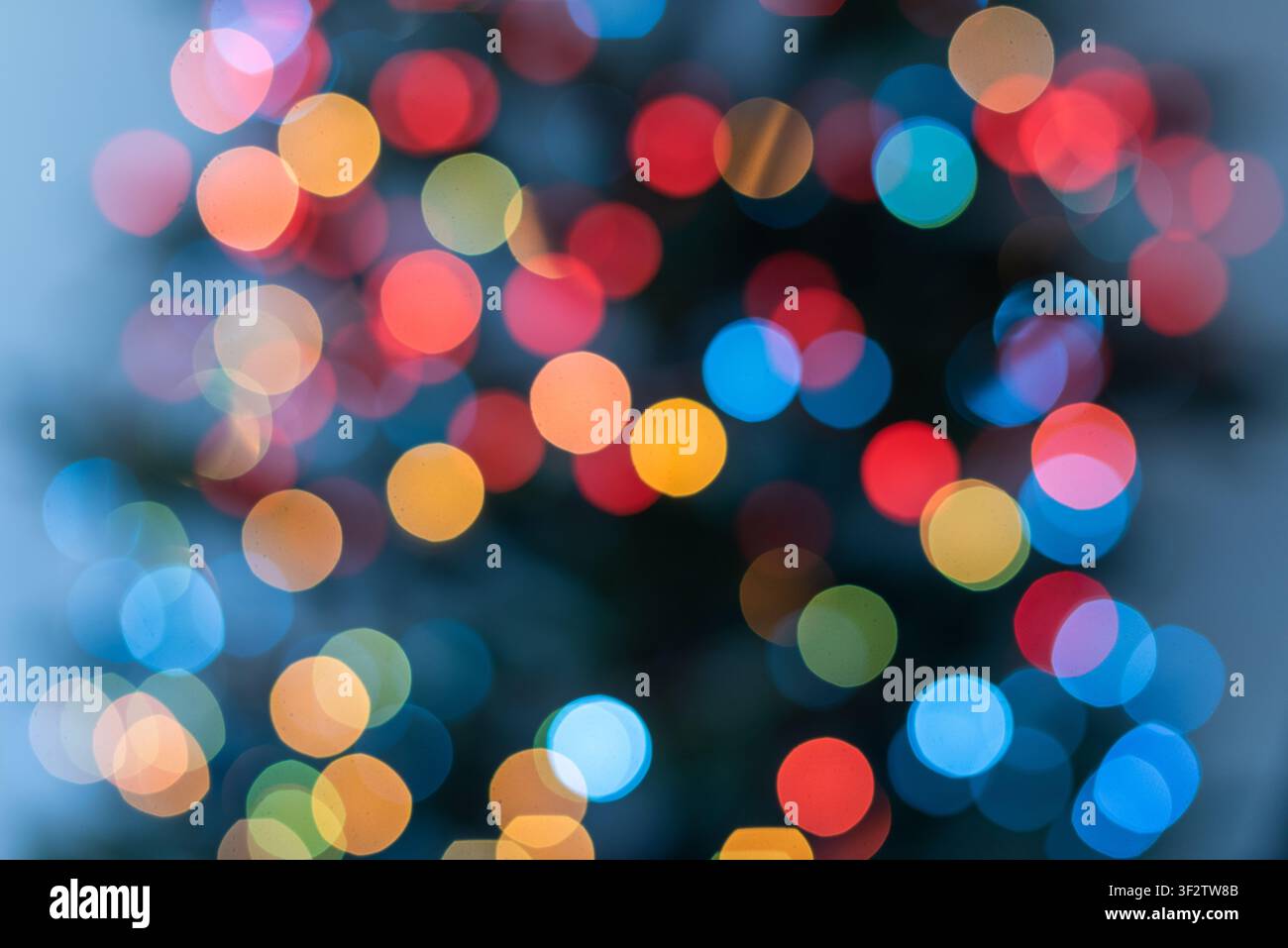 Sfondo natalizio astratto verticale con luci colorate sfocate su un albero di Natale decorato. Piccoli bokeh blu, gialli, arancioni, rossi e verdi c Foto Stock