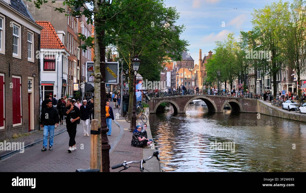 Persone che si godono una giornata estiva lungo uno dei canali storici di Amsterdam Foto Stock