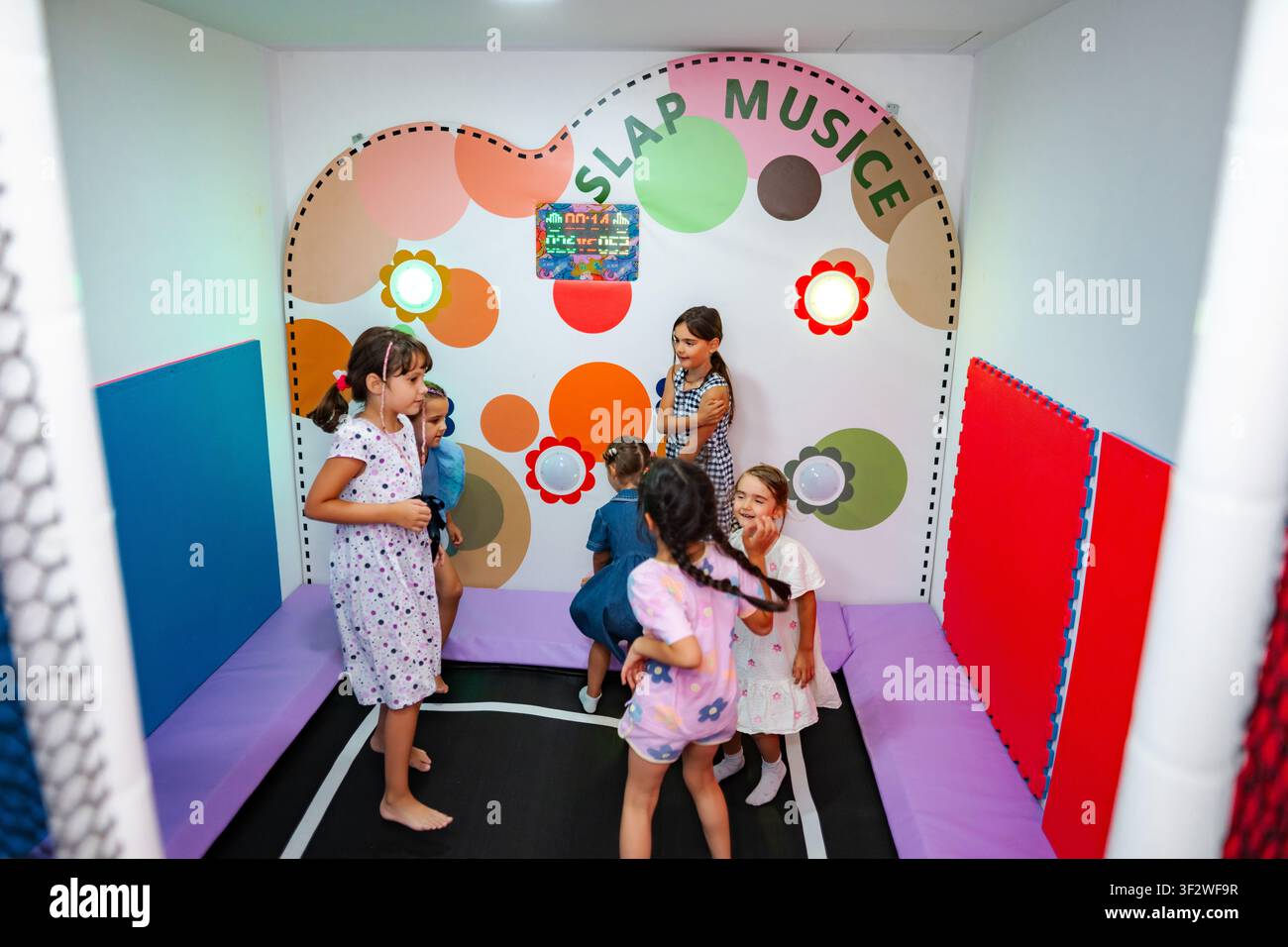 Ragazze che giocano a un gioco musicale interattivo a schiaffi in un parco giochi al coperto Foto Stock
