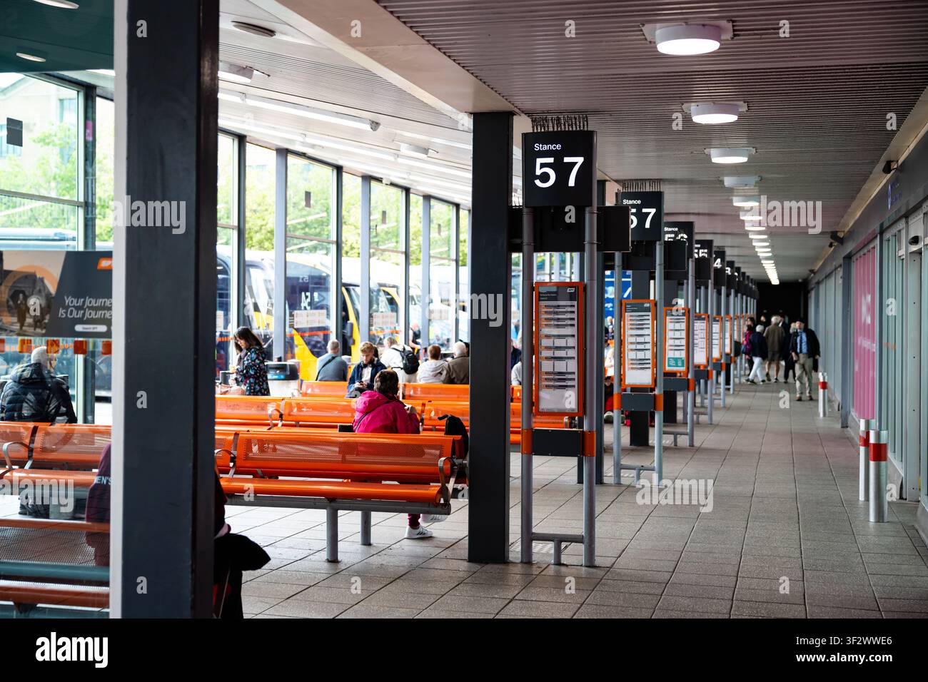 Area di attesa della stazione degli autobus con viaggiatori e sedili Foto Stock