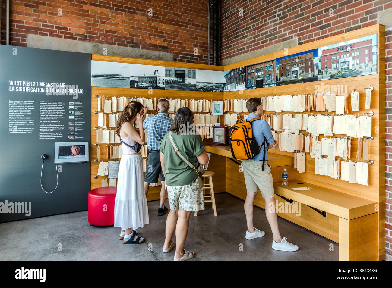I visitatori leggono ricordi personali sul muro espositivo ‚Cosa significa Pier 21 per me‘ al Museo canadese dell'immigrazione al Pier 21 di Halifax, Canada. Fotografie storiche e note manoscritte documentano l'arrivo degli immigrati nello stesso luogo. Halifax, Nuova Scozia, Canada Foto Stock