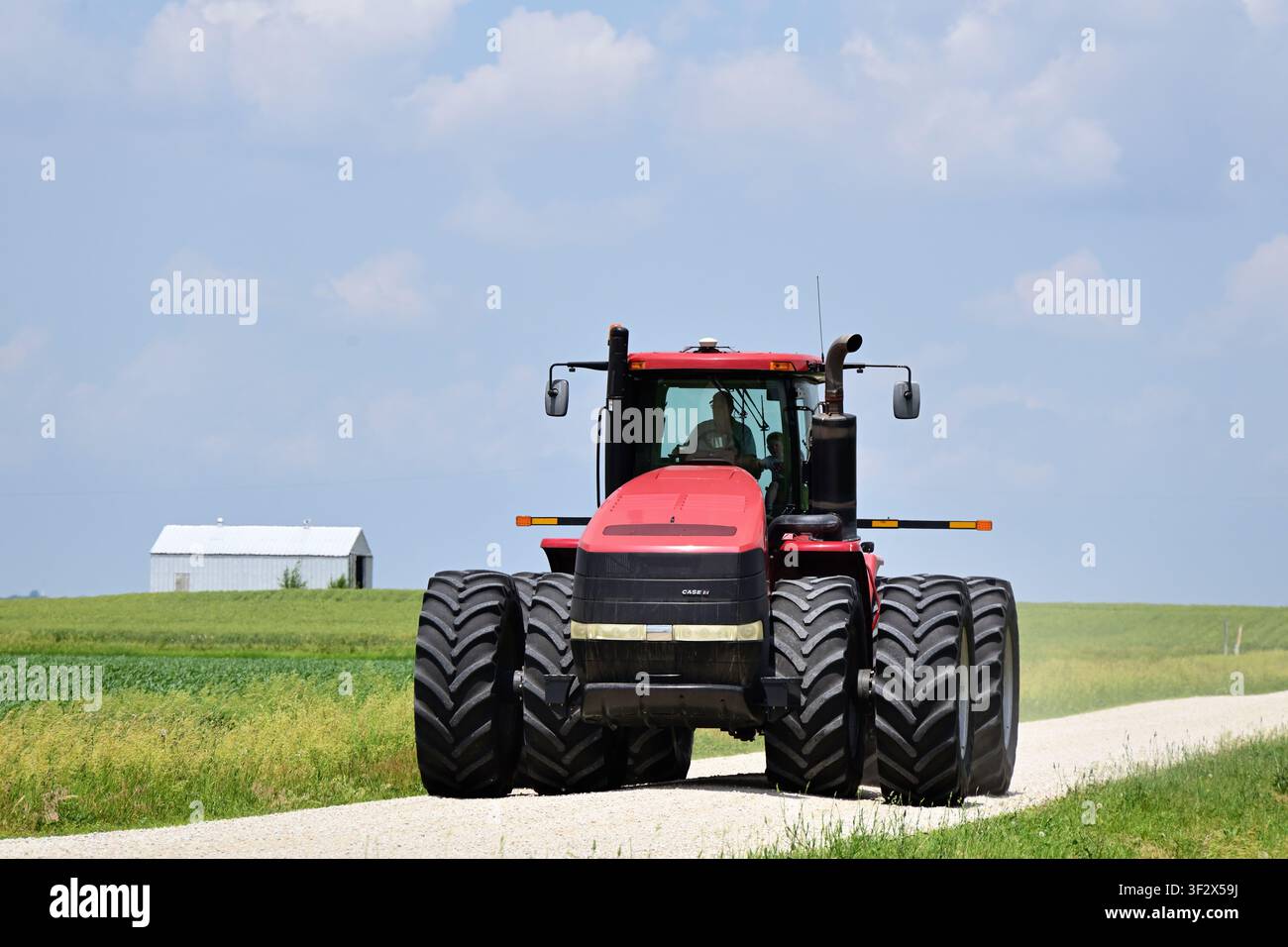 Leland, Illinois, USA. Un agricoltore, con un bambino seduto nella cabina, occupa completamente una strada sterrata rurale. Foto Stock