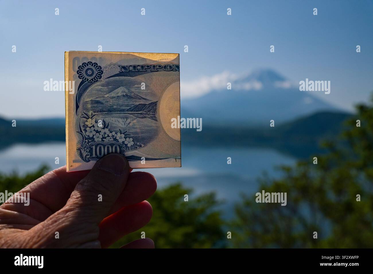 Questa vista affascinante mostra l'iconico Monte Fuji visto dal sereno Lago Motosu nella prefettura di Yamanashi, Giappone. Una banconota da 1000 yen è posizionata di proposito Foto Stock