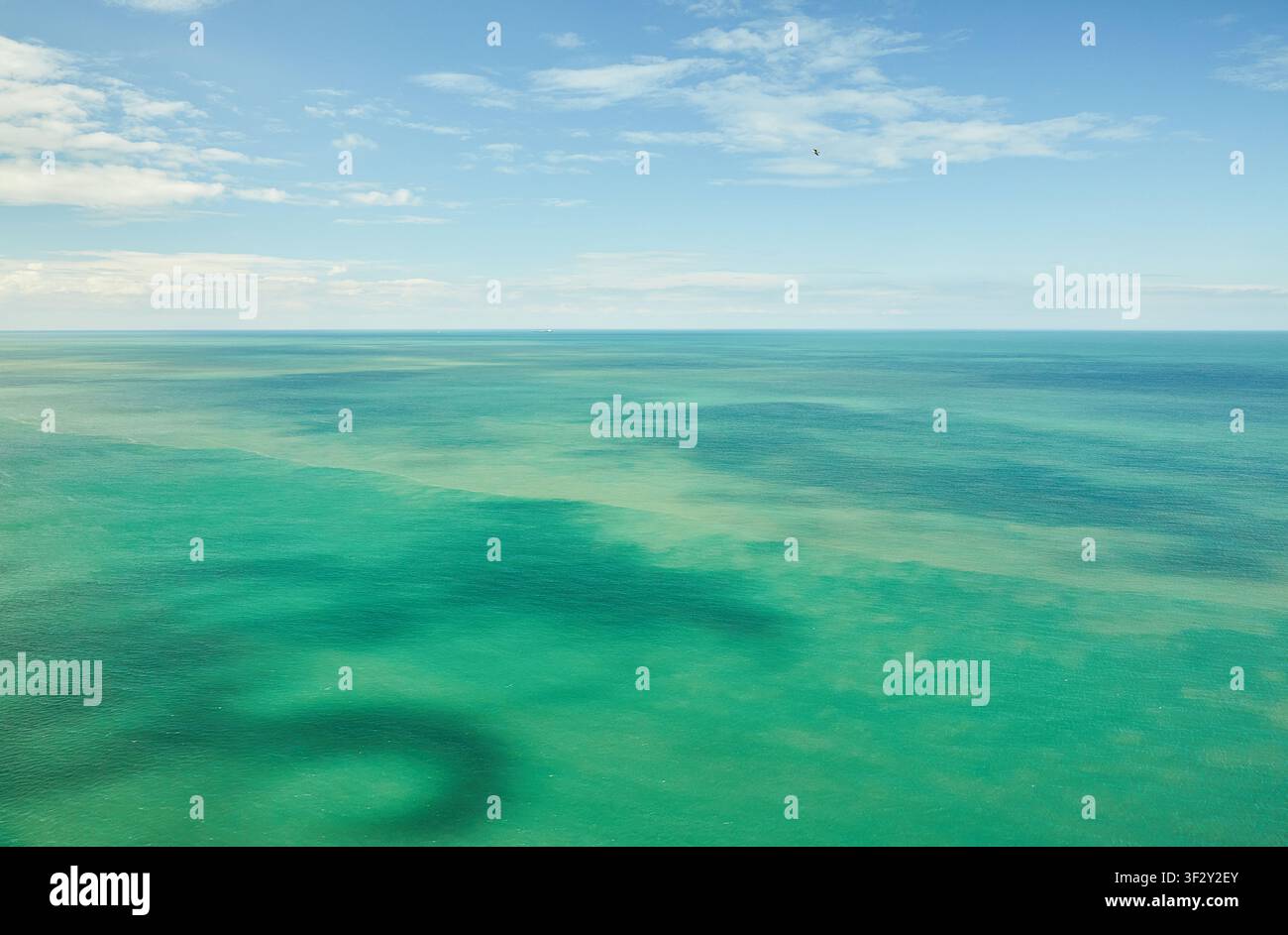 Vista aerea della superficie turchese del mare con correnti subacquee scure sotto un cielo blu a Étretat in Normandia. Foto Stock