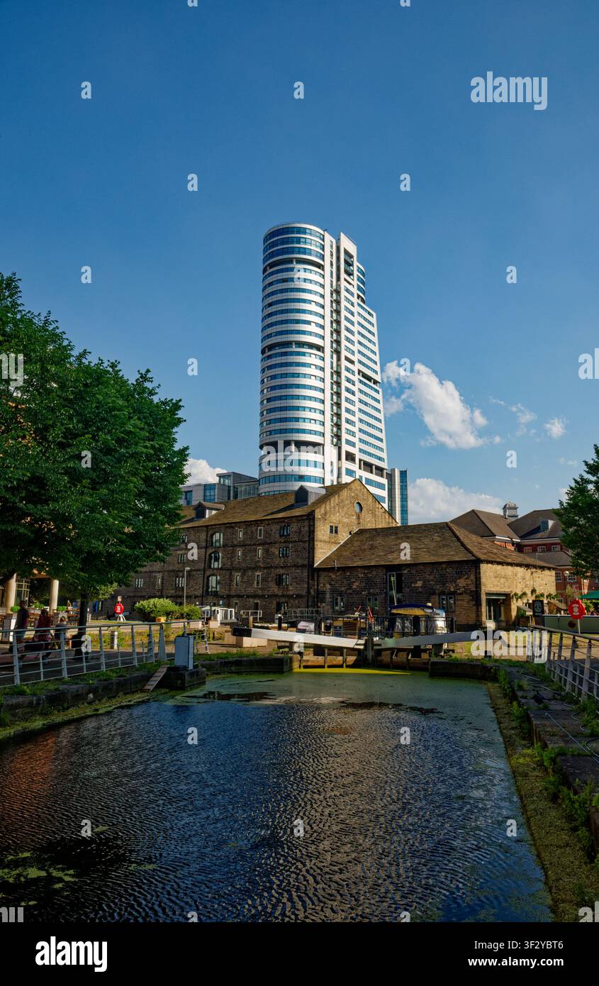 Un blocco di uffici in altezza sovrasta gli edifici più antichi sul lato del canale vicino a un bacino urbano con chiuse, Granary Wharf, Leeds, West Yorkshire. Foto Stock