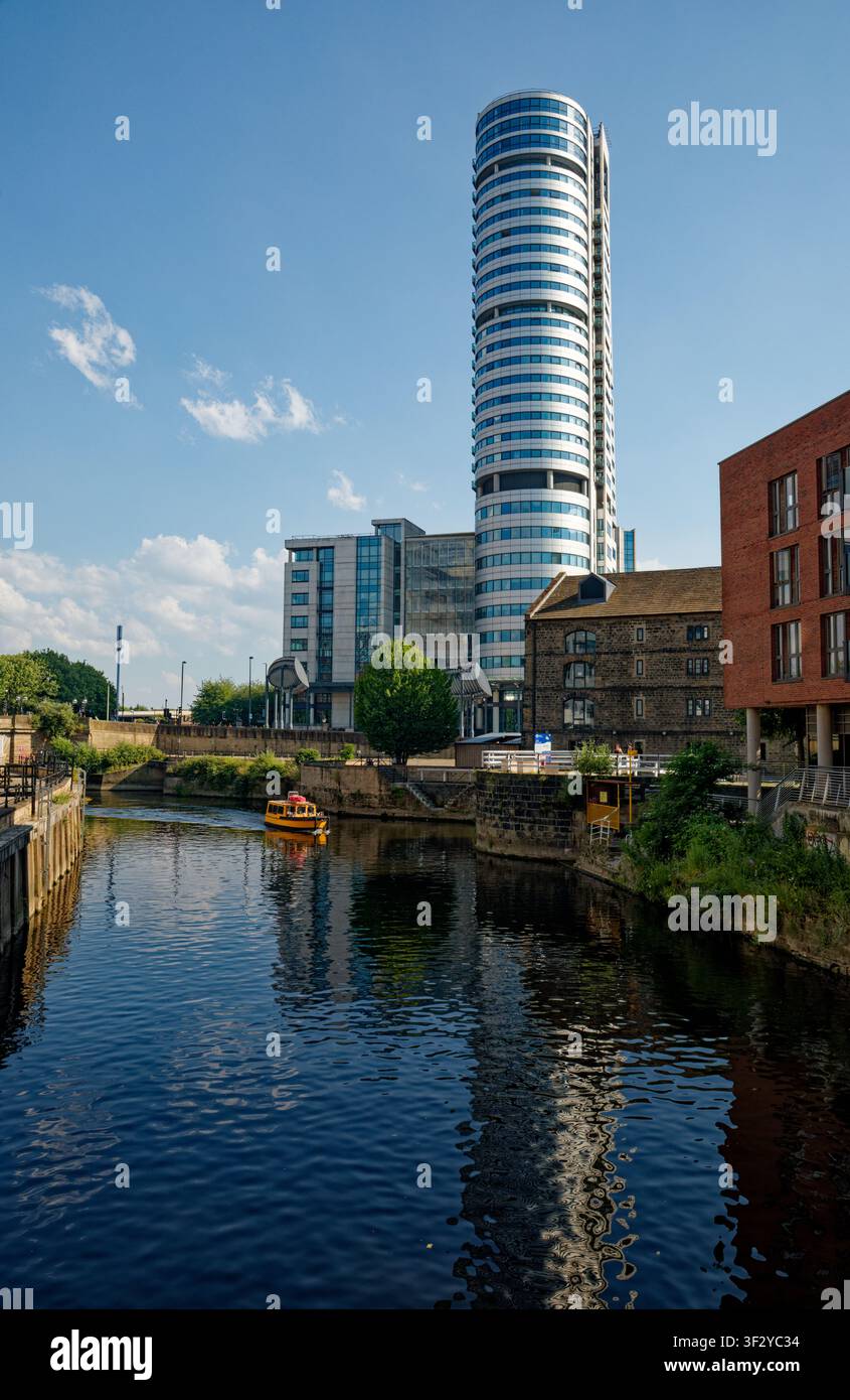 Un taxi fluviale giallo si avvicina a Granary Wharf sul fiume Aire nel centro città di Leeds, con il blocco uffici Bridgewater Place che si erge sopra, West Yorkshire. Foto Stock