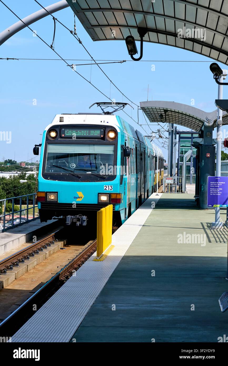 DALLAS, TX, USA - 11 LUGLIO 2026: Un treno della linea metropolitana leggera DART si avvicina a una moderna piattaforma della stazione di Dallas. Il treno, dipinto di blu e bianco, presenta Foto Stock