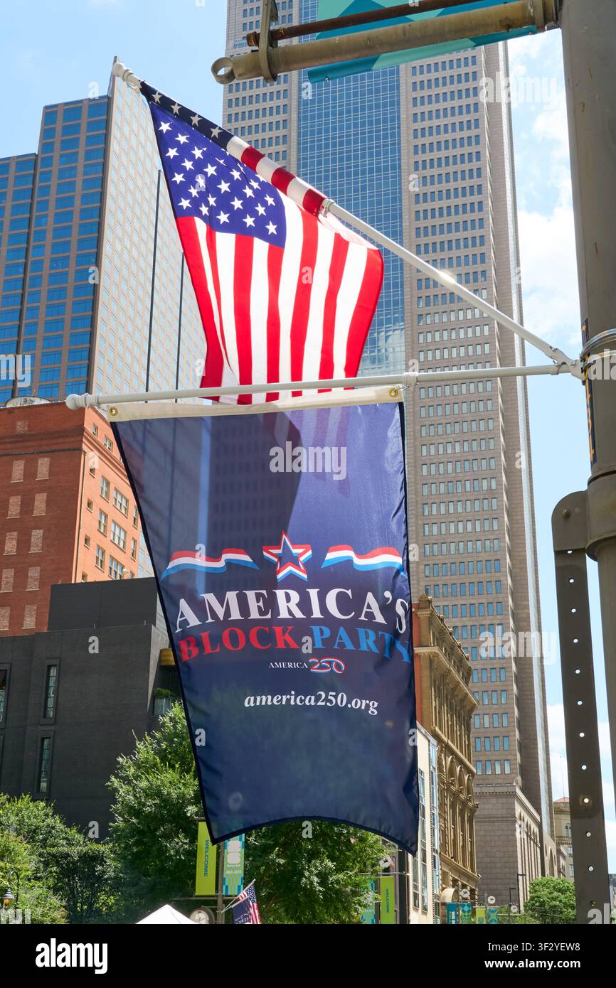 DALLAS, TX, USA - 11 LUGLIO 2026: Uno striscione dell'America's Block Party e una bandiera americana esposti in modo prominente sullo sfondo dei grattacieli del centro città Foto Stock