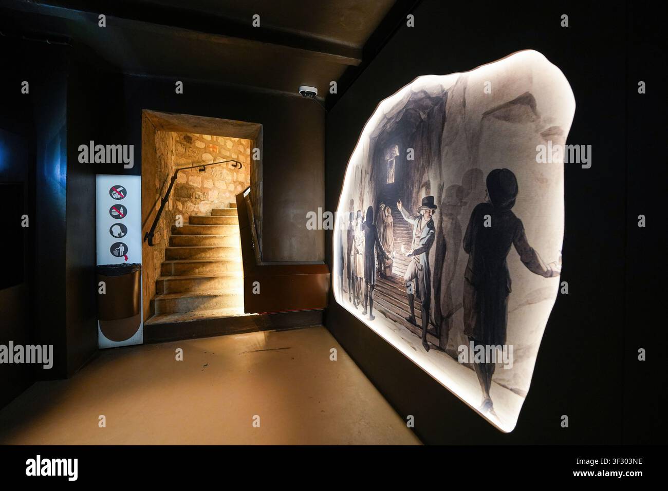 Corridoio espositivo con pannello illustrativo storico e scala in pietra nelle Catacombe di Parigi, Francia Foto Stock