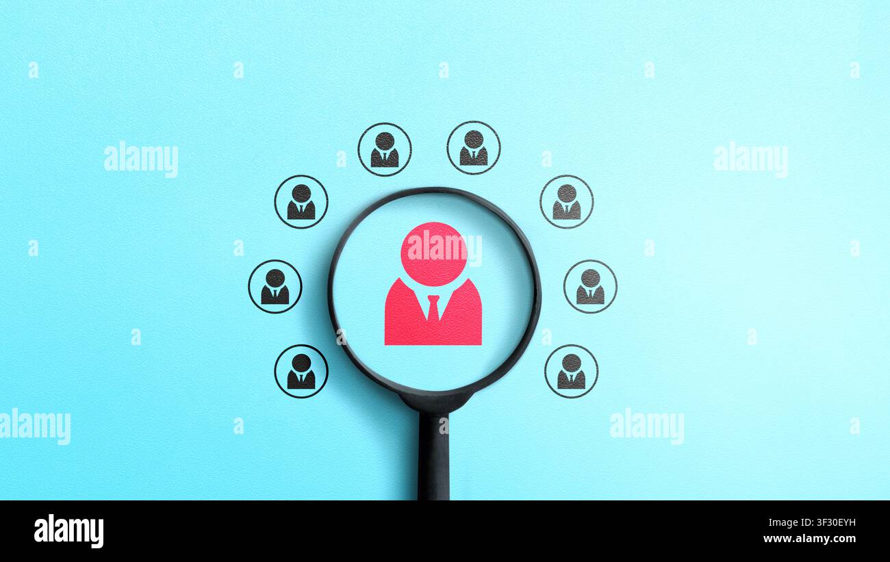 Lente d'ingrandimento focalizzata su un'icona di persona rossa tra diverse icone nere su uno sfondo blu, che rappresenta la ricerca di talenti, l'assunzione e la selezione in hu Foto Stock