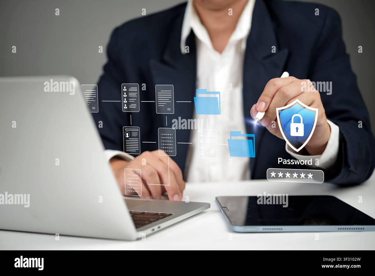 Uomo d'affari che utilizza un laptop e un tablet con una cartella virtuale di documenti e un ologramma di scudo della password. Concetto di sicurezza dei dati, cybersecurity, file aziendale Foto Stock