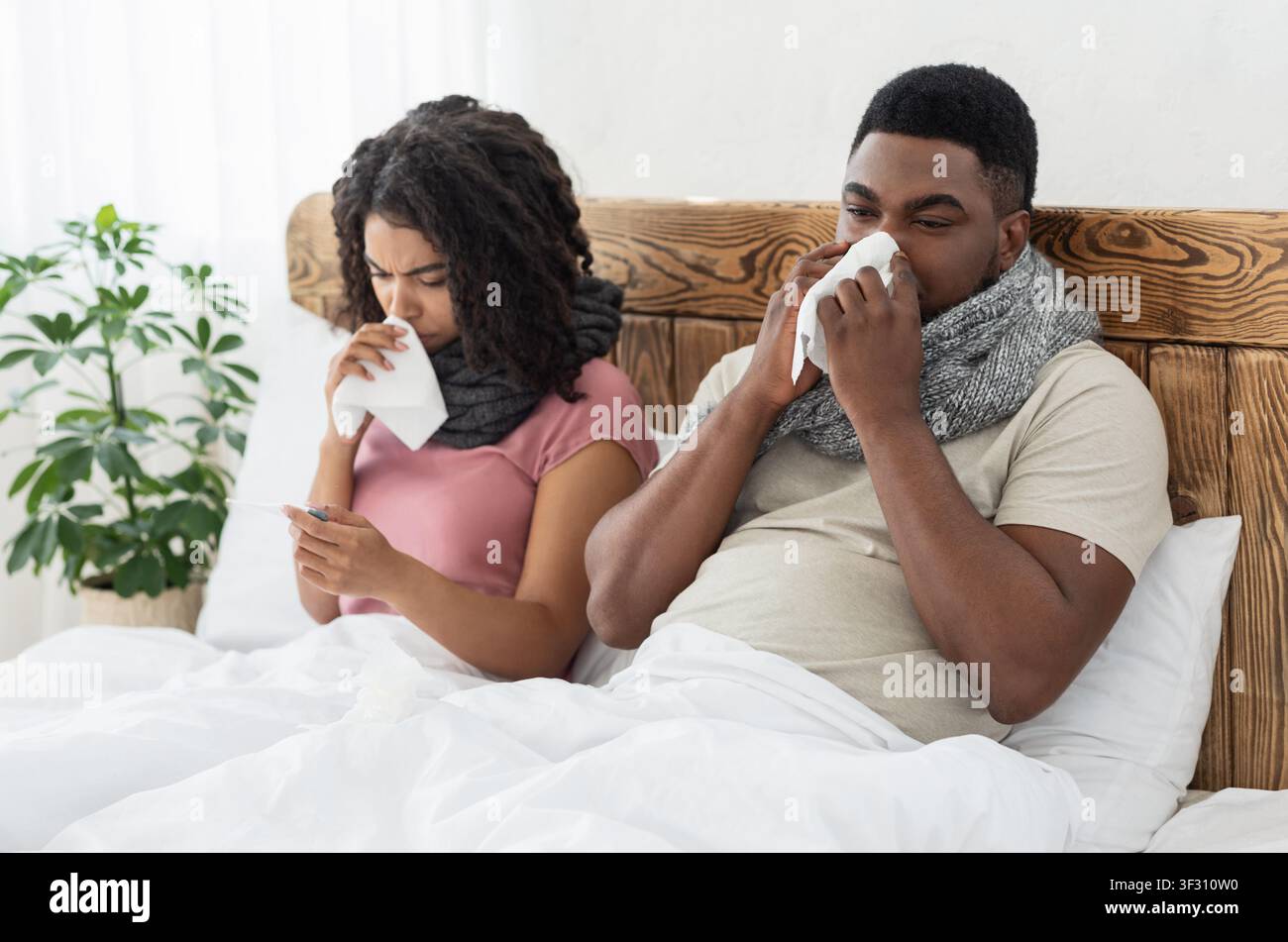 Malata coppia afro-americana avvolta in sciarpe seduti a letto Foto Stock