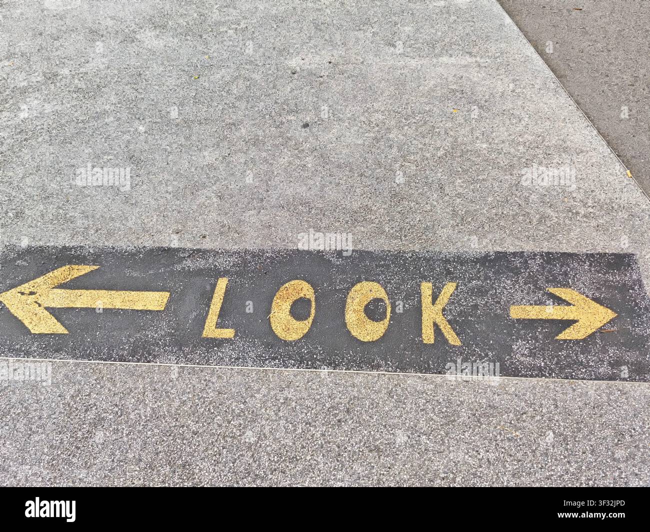 Lettere gialle su una superficie grigia mostrano la parola “look” con frecce che puntano a sinistra e a destra in una strada cittadina affollata. Foto Stock
