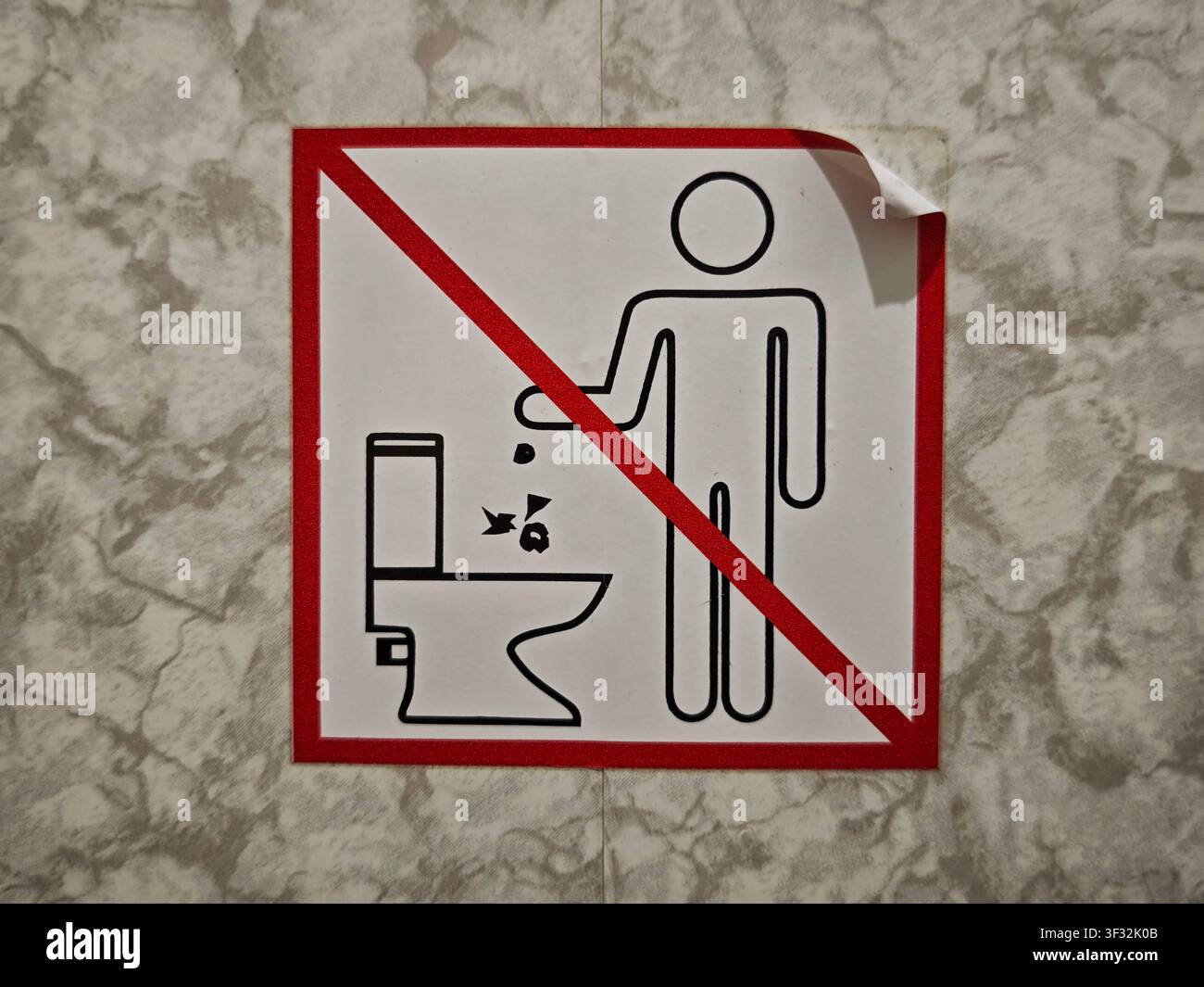 Un cartello ricorda alle persone di non gettare spazzatura nel water in un bagno pubblico. L'immagine mostra una semplice grafica di una persona e di un gabinetto. Foto Stock