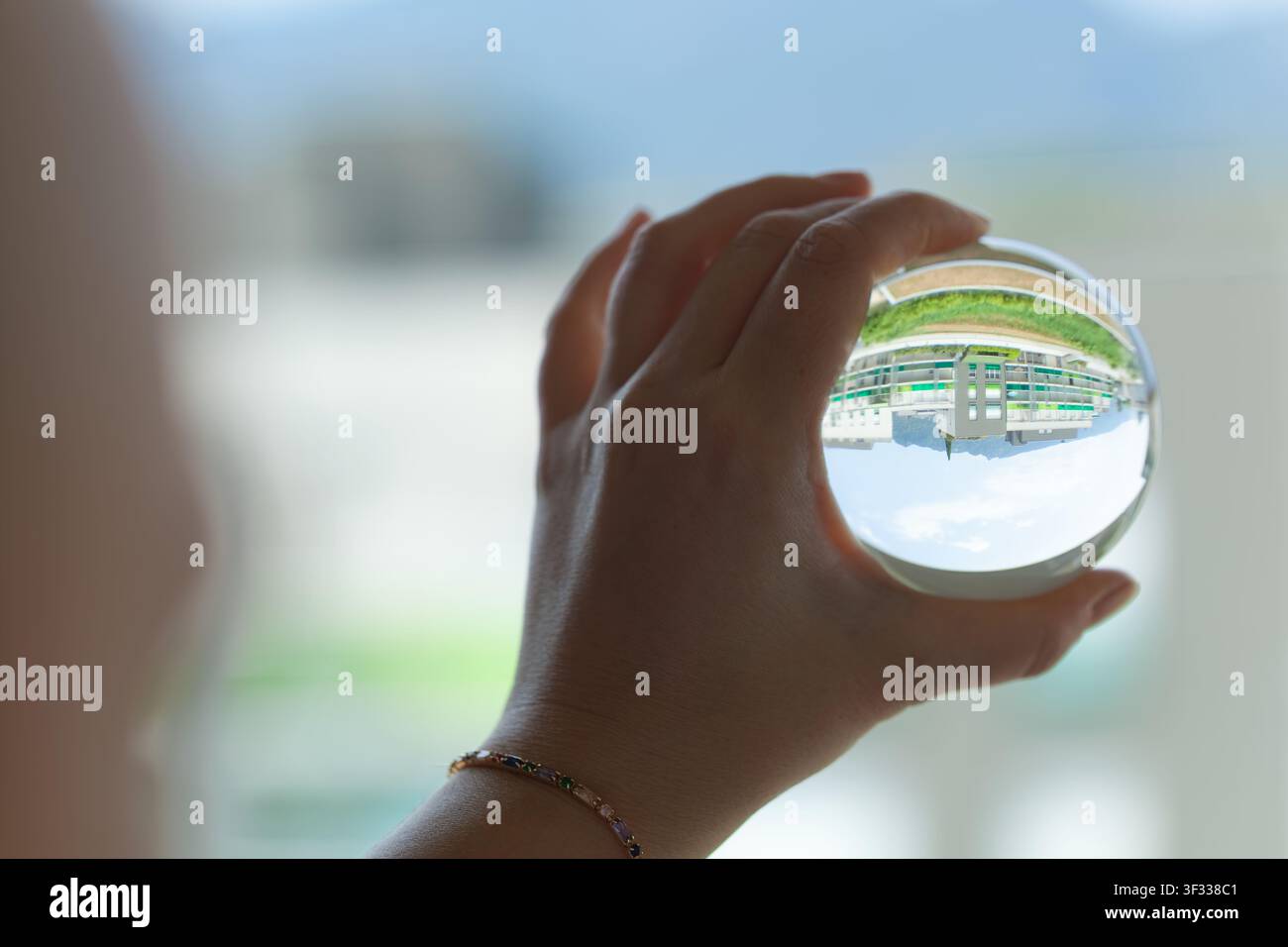 Mano che tiene una sfera di cristallo con paesaggio invertito Foto Stock