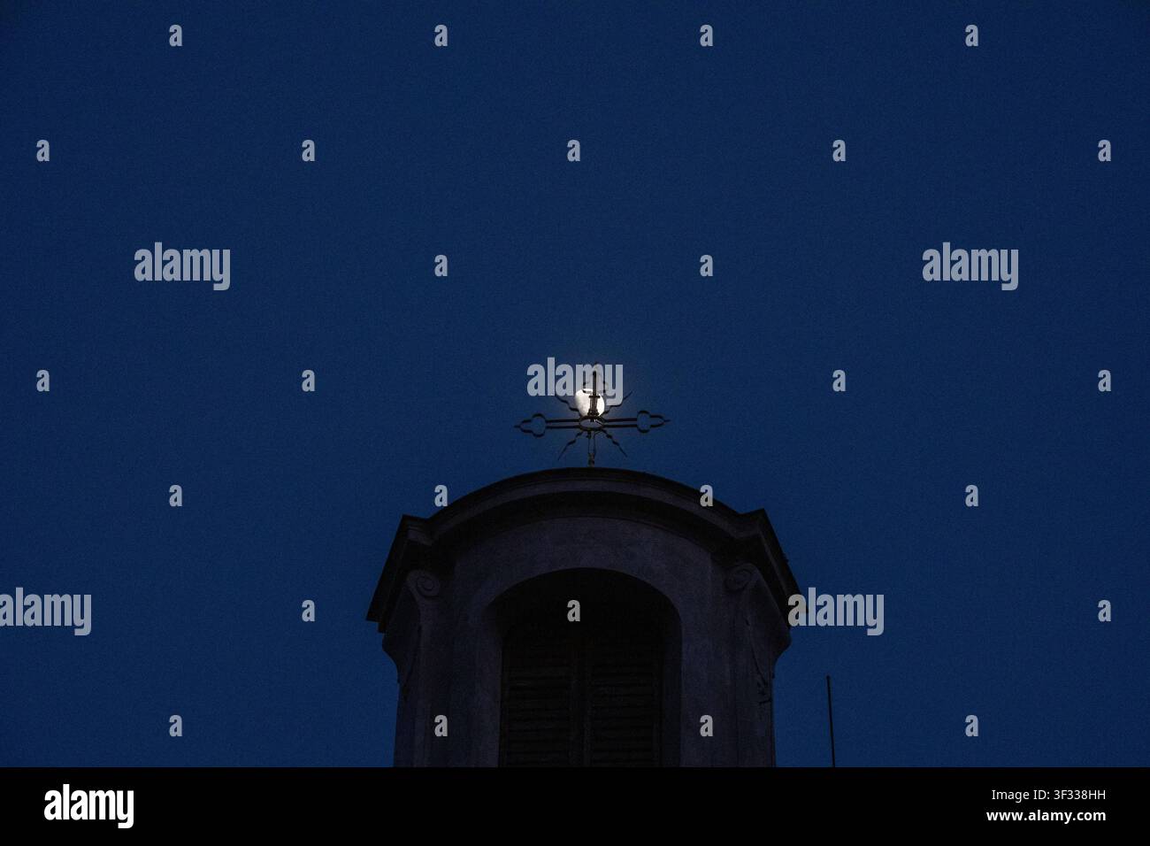 Luna che si allinea con una croce di chiesa contro un cielo blu profondo al tramonto Foto Stock