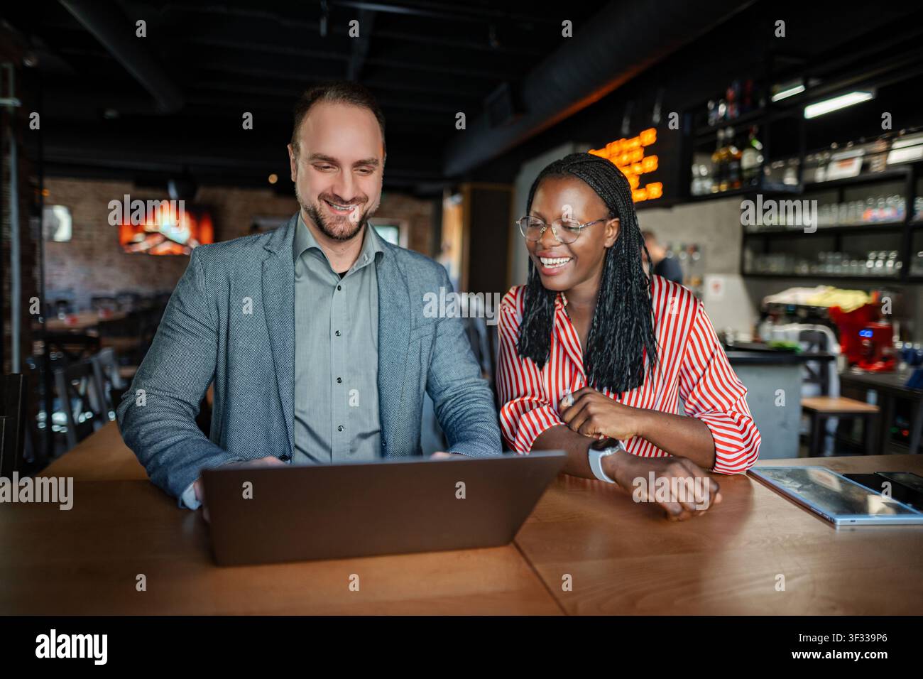 Diversi professionisti aziendali che collaborano con notebook in un bar Foto Stock