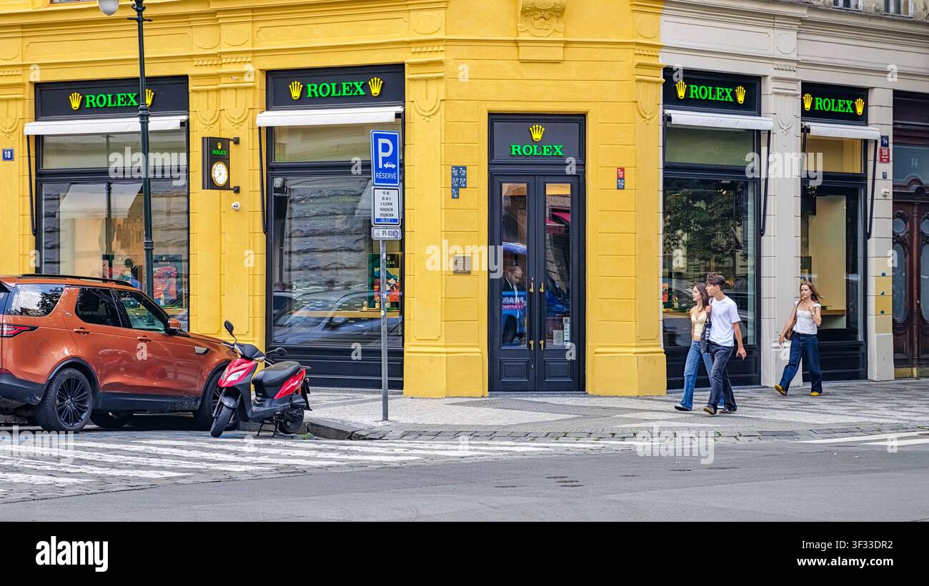 Praga, Repubblica Ceca - 21 luglio 2026: Boutique ROLEX con insegne luminose verdi del marchio e l'iconico logo della corona d'oro. Un orologio ROLEX montato a parete Foto Stock