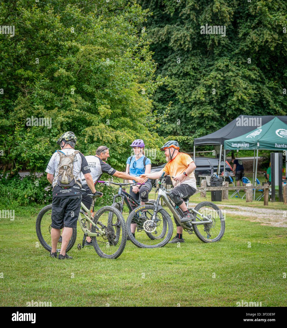 Un gruppo di quattro mountain biker si incontrano a un evento di mountain bike, si salutano e si stringono la mano. Foto Stock