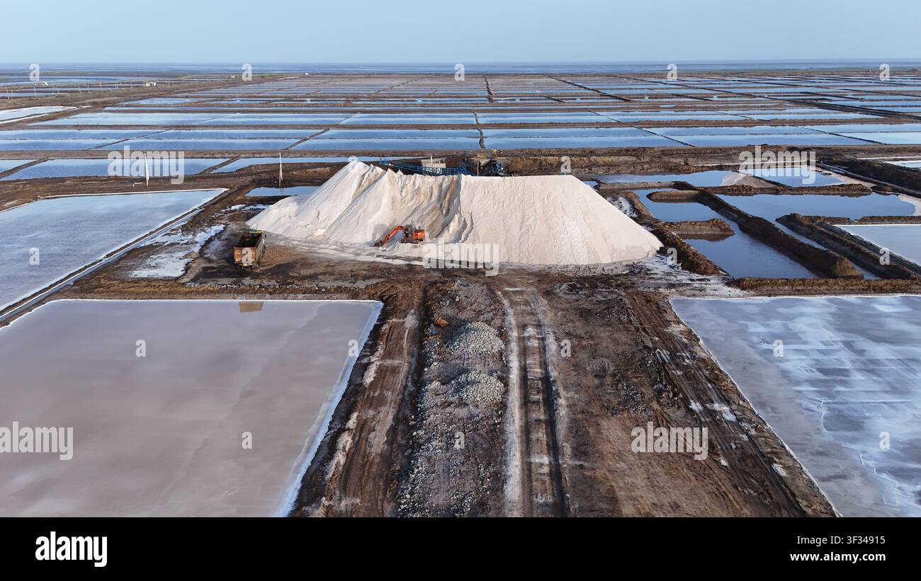 Vista a droni dei campi di produzione del sale con grandi cumuli bianchi di sale e paesaggio industriale Foto Stock