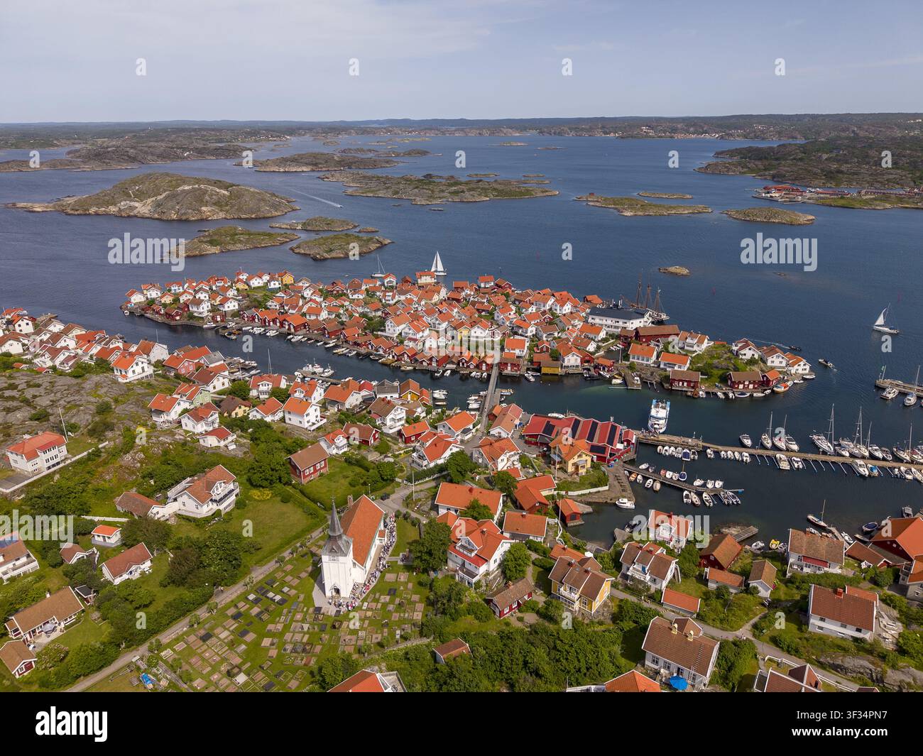 Vista aerea del villaggio costiero con le sue tradizionali case di legno rosse, la chiesa storica e il porticciolo annidato tra isole rocciose a Gullholmen, Vast Foto Stock