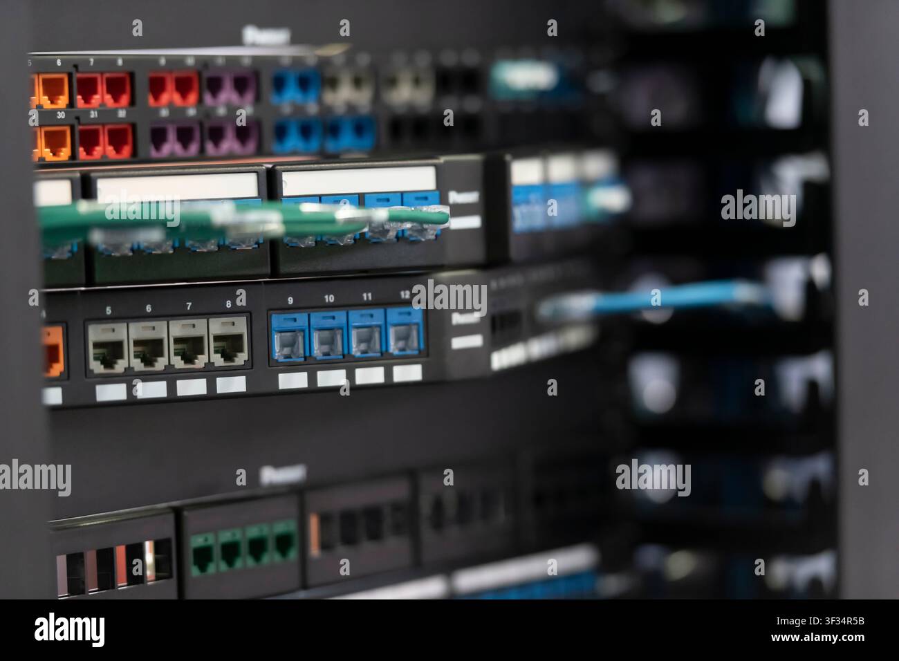 Primo piano di pannelli di connessione di rete montati su rack con porte colorate e connessioni in fibra ottica, display dell'hardware di telecomunicazione. Foto Stock