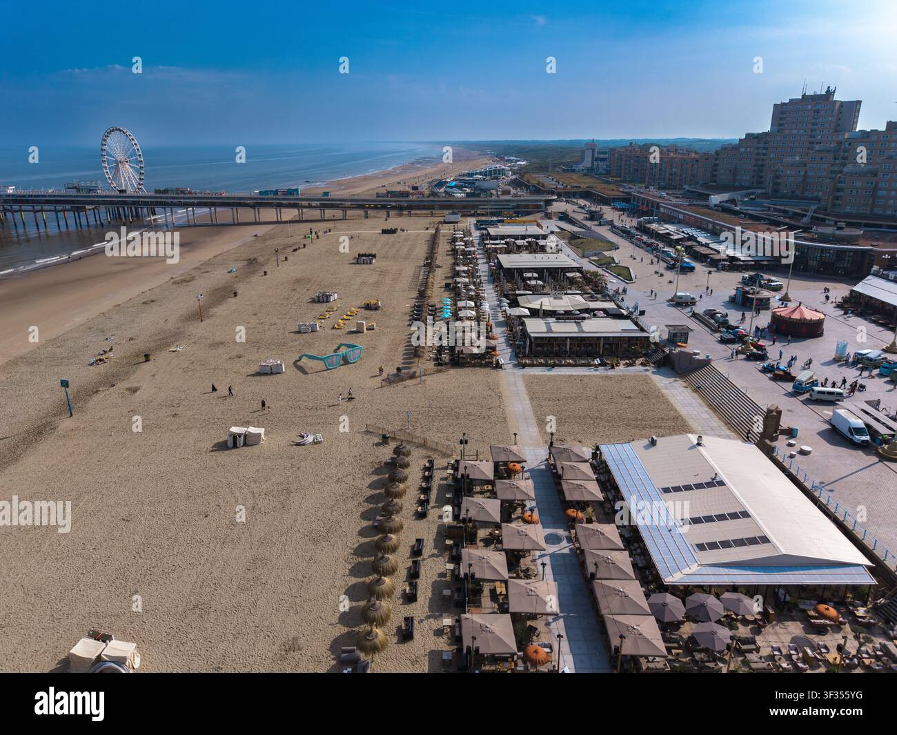 Una magnifica fotografia aerea grandangolare che cattura una panoramica da drone ad alta quota di una famosa spiaggia di resort costiero, un lungo viale promenade e ghiaccio Foto Stock