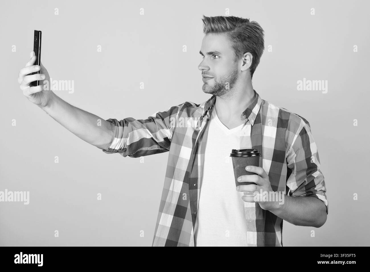 Un uomo millenario che fa selfie. Blog video. Comunicazione videochiamata. Uomo che fa video blog isolato sul giallo. Selfie su smartphone. Bloggare sui selfie Foto Stock