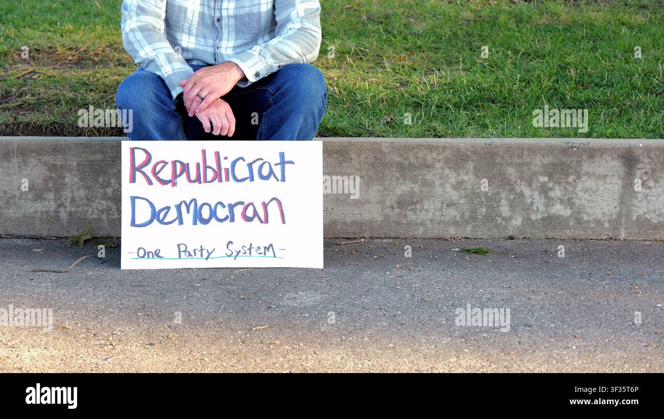 Manifestante tiene un cartello fatto a mano con la scritta "Republicrat Democran One Party System" che protesta contro l'influenza delle aziende sul duopolio politico delle elezioni e la scelta Foto Stock