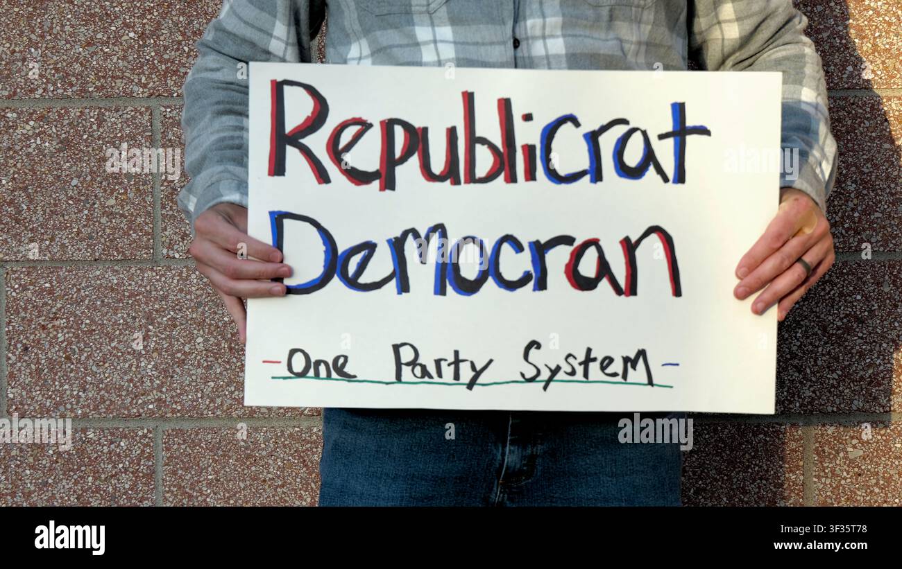 Manifestante tiene un cartello fatto a mano con la scritta "Republicrat Democran One Party System" che protesta contro l'influenza delle aziende sul duopolio politico delle elezioni e la scelta Foto Stock