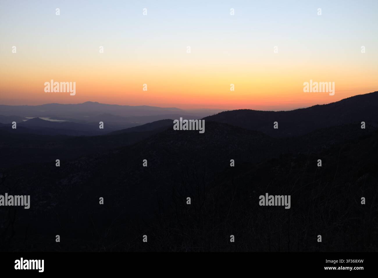 Trascinante tramonto sfumato su strati di montagne in silhouette Foto Stock
