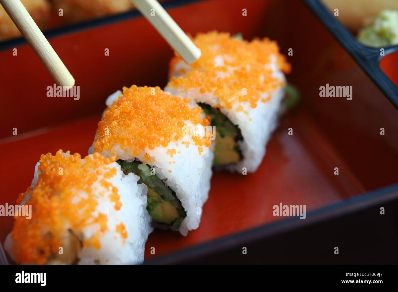 Le persone si godono il sushi con le bacchette in un ambiente da ristorante Foto Stock