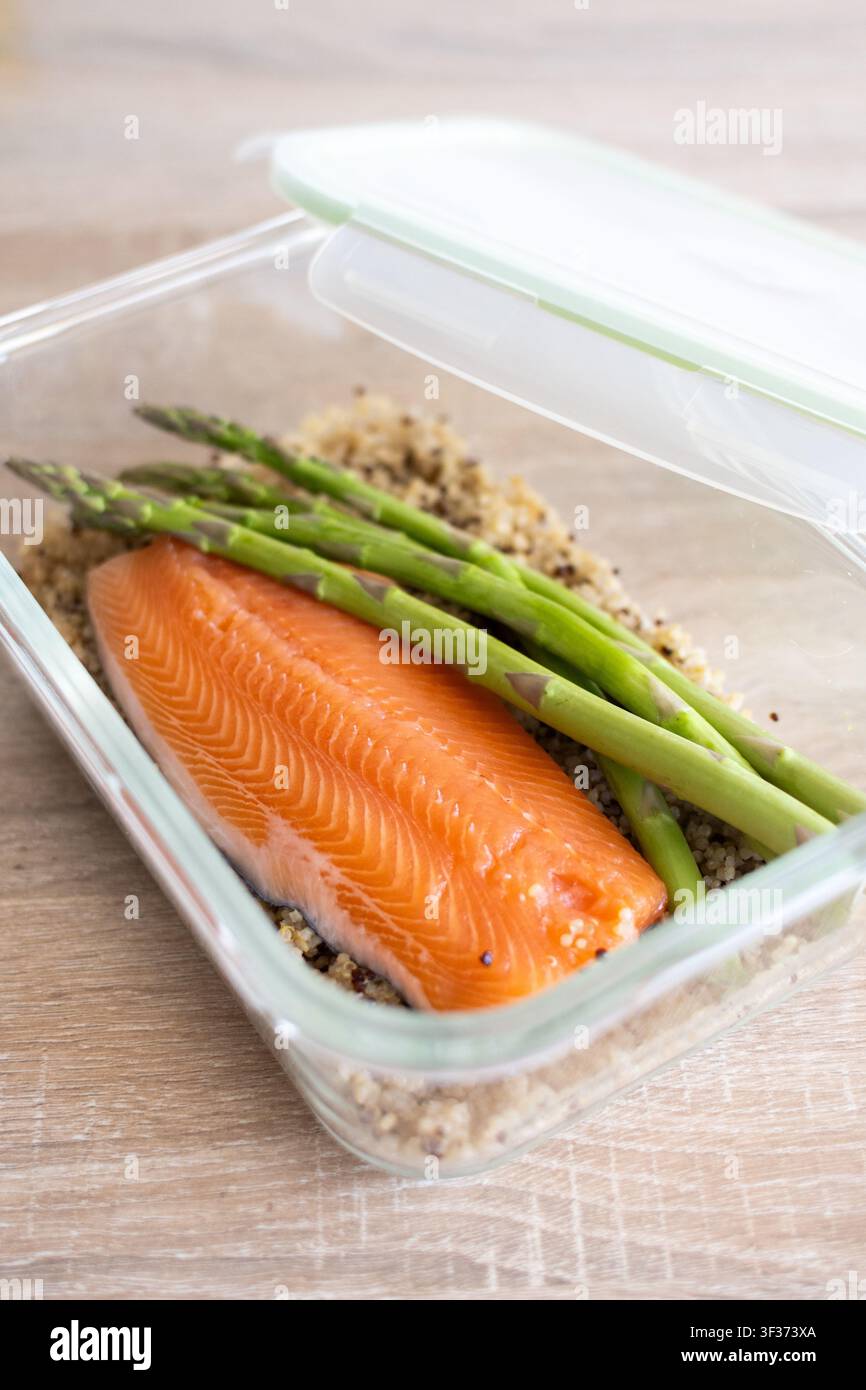 Preparazione sana di pasti a base di salmone con quinoa e asparagi in contenitore di vetro Foto Stock