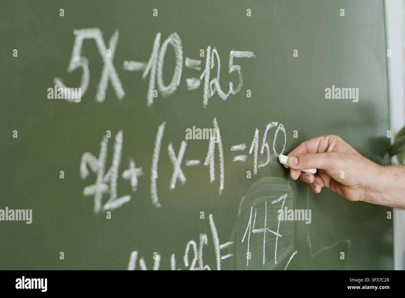 Insegnante che scrive equazioni matematiche alla lavagna per l'educazione Foto Stock