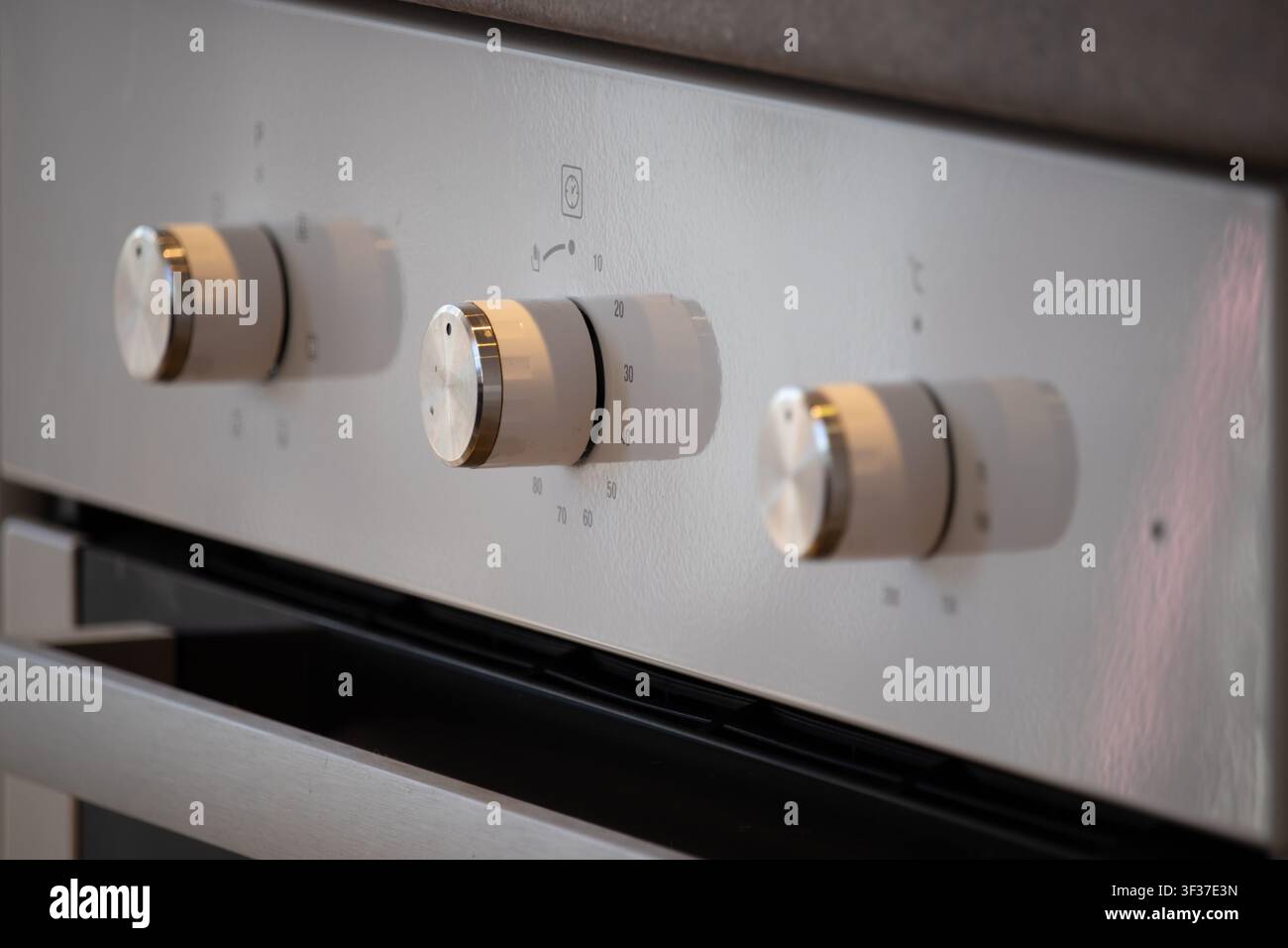 Primo piano di tre quadranti moderni bianchi e argento sul pannello di controllo del forno, con funzione timer visibile Foto Stock