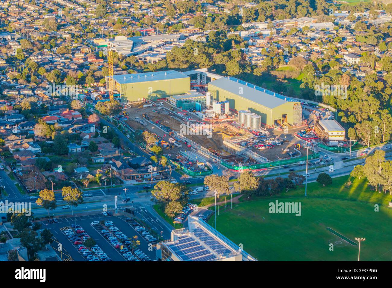 Una prospettiva aerea di un cantiere per la costruzione di un anello ferroviario suburbano, che evidenzia lo sviluppo industriale tra case residenziali e spazi verdi Foto Stock