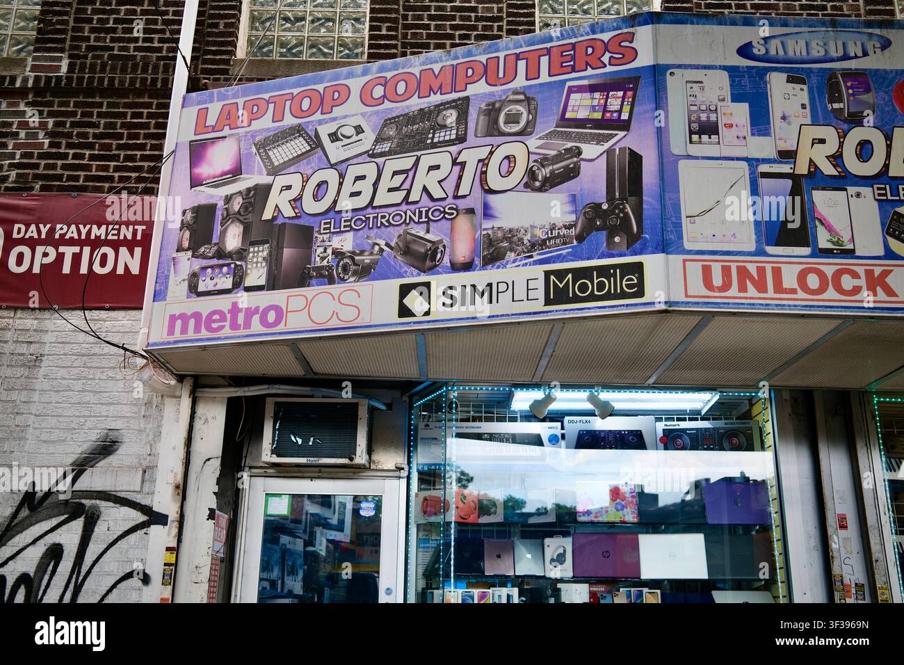 Queens, New York, USA – 9 luglio 2025: Vetrina di un negozio di elettronica che pubblicizza servizi mobili e prepagati Foto Stock