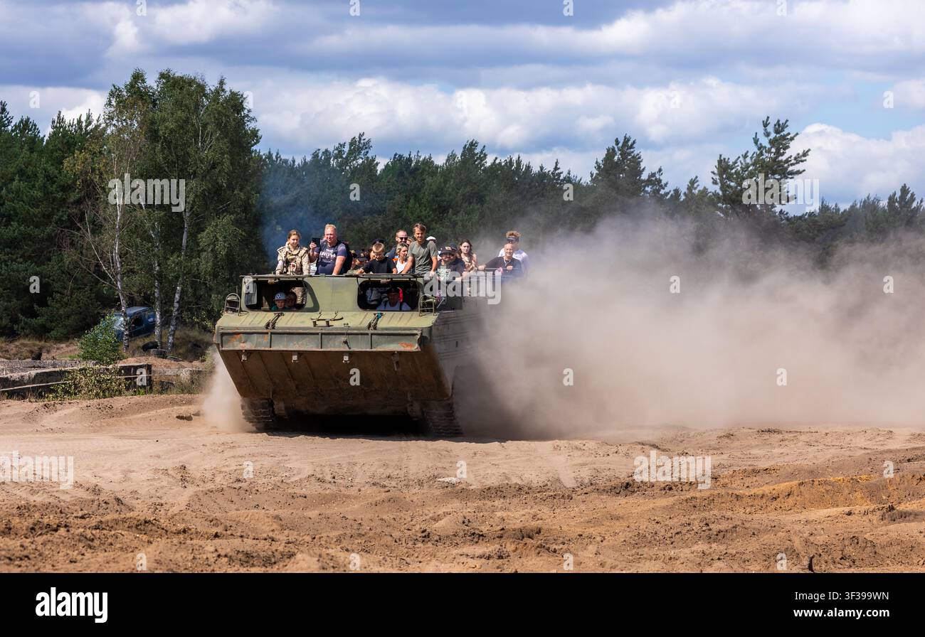 Borne Sulinowo, Polonia – 13 agosto 2023: Persone che vivono un'escursione fuoristrada in un veicolo blindato da trasporto truppe, sollevando polvere Foto Stock